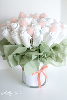 a bouquet of white and pink flowers in a glass vase with ribbon on the side