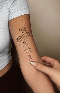 a woman's arm with flowers on it and a small tattoo in the middle