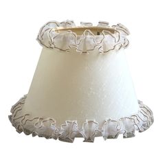 a white lamp shade with ruffled trim