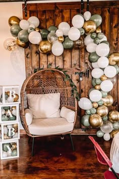 a room filled with lots of balloons hanging from the ceiling next to a wicker chair