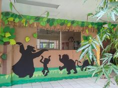 the mural on the wall depicts children's silhouettes playing with each other in front of a classroom