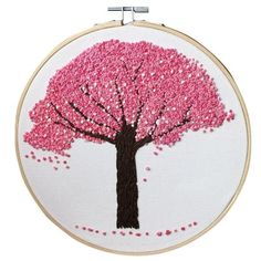 a pink tree with lots of leaves on it is shown in a white hoop hanging from the wall