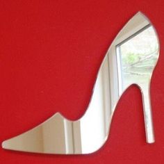 a high heeled shoe shaped mirror mounted to a red wall next to a window