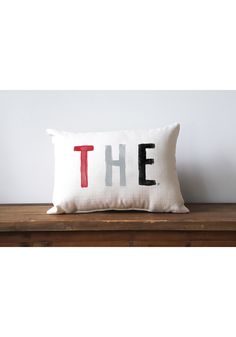 a pillow that says the on it sitting on top of a wooden table next to a white wall