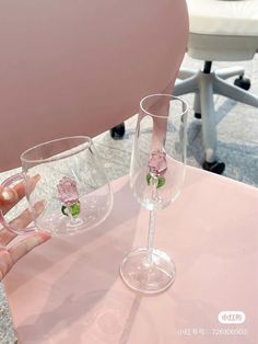 two wine glasses sitting on top of a pink table