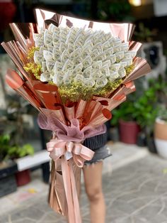 a woman holding a bouquet of flowers in her hand and wearing shorts on the sidewalk