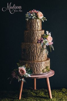 a three tiered wedding cake with flowers on top and moss growing all around it