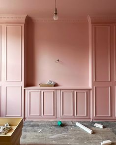 a room with pink walls and wooden furniture on the floor in front of it is being painted