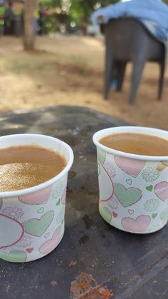 two cups filled with liquid sitting on top of a wooden table next to an elephant