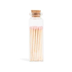 several matches in a glass jar on a white background with a corked top and wooden stick sticking out from the bottom