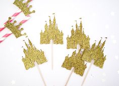 gold glitter castle cupcake toppers with pink and white striped straws in the background