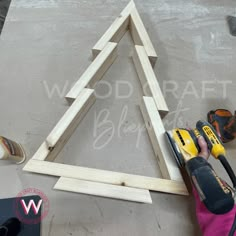 a person using a power drill to build a wooden christmas tree