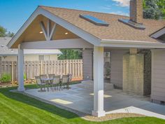 a patio with a table and chairs under a covered area in front of a house