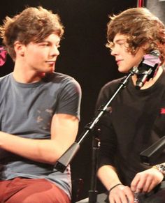 two young men sitting next to each other in front of microphones