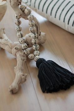 a black and white tasseled bead necklace laying on the floor next to a pillow