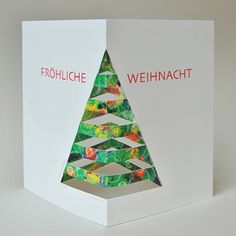 a white box with a christmas tree cut out of it's sides and the words frohlche weinhacht on top