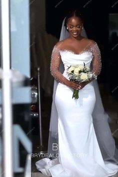 a woman in a white wedding dress is standing outside the door with her bouquet and veil on