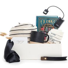 a white box filled with books and other items next to a black ribbon tied around it