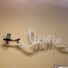 an airplane is flying in the air next to a wall that says love written on it