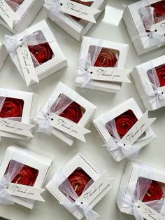 red roses in white boxes with ribbons tied around the edges and tags on each box