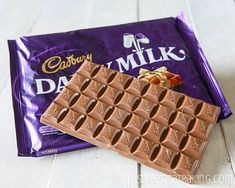 a bar of cadbury's dairy milk chocolate on a white wooden table next to it