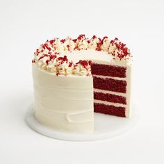 a red velvet layer cake with white frosting and sprinkles on top