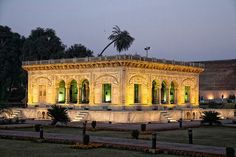 an old building lit up at night with palm trees in the background