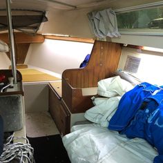 the inside of a small boat with lots of stuff on the bed and desks