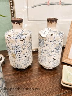 two blue and white vases sitting on top of a wooden table next to a mirror