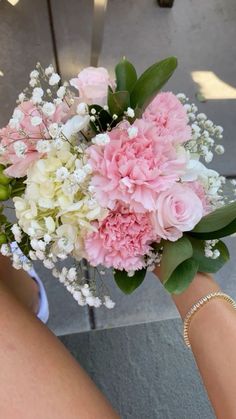 a bouquet of pink and white flowers being held by someone's arm