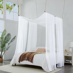 a white bed sitting in a bedroom on top of a hard wood floor next to a window