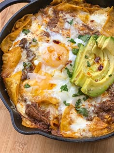 an omelet with meat, cheese and avocado in a cast iron skillet