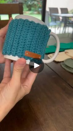 a person holding up a knitted coffee cup