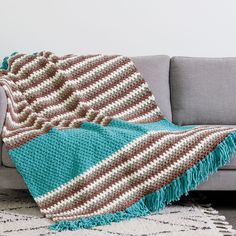 a couch with a blanket on top of it and a rug in front of it