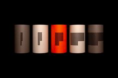 four different colored tubes with black and white designs on the top one is red, the other is orange