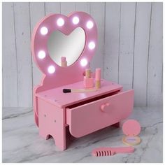 Vanity Dimensions: 17" x 11.38" x 6.81" Power Source: 2 AAA 1.5V Batteries (Not Included) Material: MDF, Plywood & Plastic Color: Pink & White Pattern: Polka Dot Age Grade: 3+ Quantity: 1 Set Set Includes: 1 - Vanity 1 - Perfume Bottle 1 - Lipstick 1 - Comb 1 - Compact 1 - Nail Polish Surprise your fashionable kiddo with a unique toy, such as this Heart Light Up Makeup Vanity Play Set! This fun set features a pink vanity with a heart-shaped mirror to match the knob on the drawer. There is a button on the mirror that you can press to make the lights shine with a brilliant glow. Opening the drawer reveals fun accessories, such as a compact and lipstick that you can play with to pretend you're doing your makeup. Make play time a blast with this engaging toy set!   *No discounts may be applied Vanity Dimensions, Cute Vanity, Pink Vanity, Play Makeup, Mdf Plywood, Shaped Mirror, Dream Life House, Heart Lights, Fun Accessories