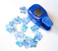 a blue plastic container filled with lots of small glass flowers on top of a white table