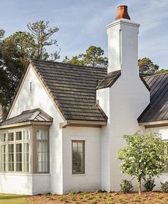 a white house with a black roof and chimney