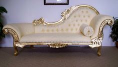 a white and gold couch sitting next to a potted plant on top of a carpeted floor