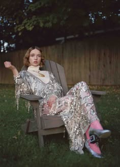 a woman sitting in a lawn chair with her legs spread out, wearing silver sequins