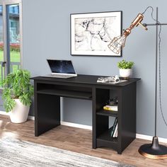 a laptop computer sitting on top of a desk next to a lamp and potted plant