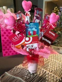 a vase filled with candy and candies on top of a table next to a pink gift bag