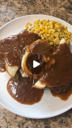 a white plate topped with meat covered in gravy and corn