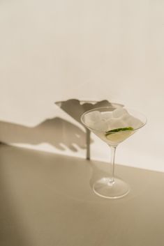 a glass filled with liquid sitting on top of a table next to a shadow cast by a hand