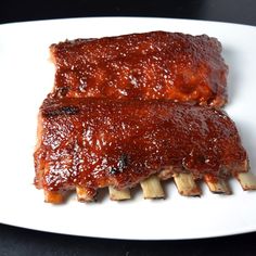 two ribs covered in bbq sauce on a white plate