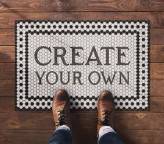 a person standing in front of a door mat that says create your own