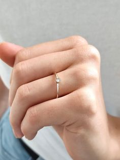 a woman's hand with a diamond ring on her finger, holding something in the other hand