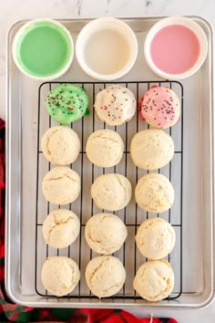 doughnuts on a cooling rack with sprinkles next to green and pink cups