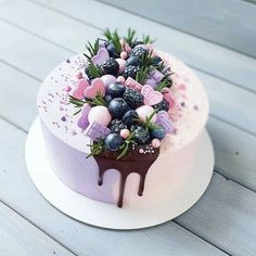 a cake decorated with berries and chocolate drips