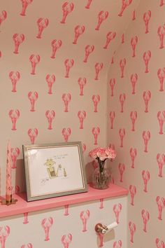 a bathroom with pink and white wallpaper, toilet paper and candles on the shelf